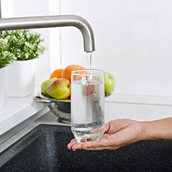 Photo of someone filling a glass of water from kitchen tap